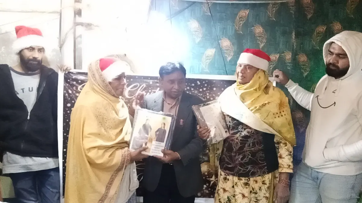 An elderly woman receiving a Bible and Christmas gift from ministry workers