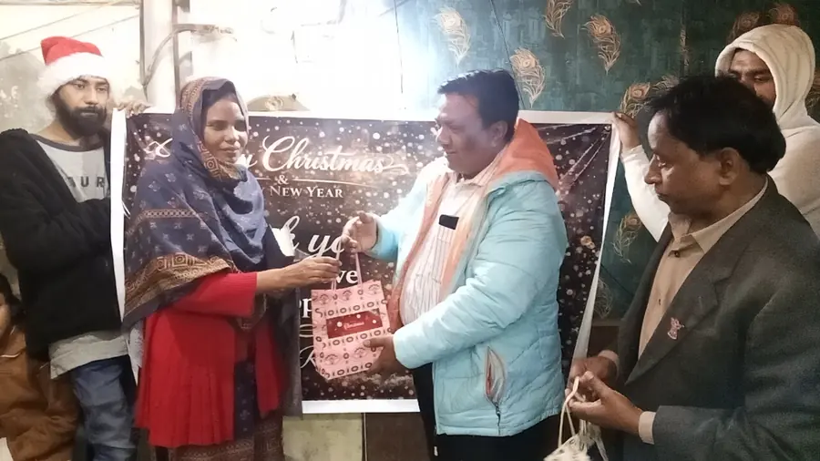 A woman receiving a gift bag from ministry workers in front of a Christmas banner