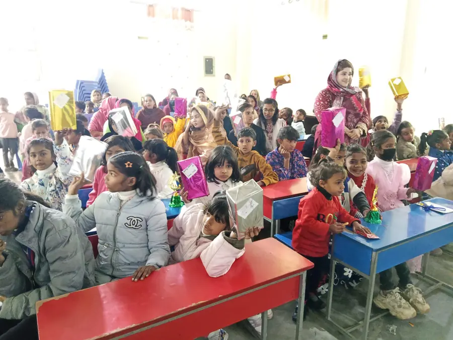 A large group of children seated at classroom tables holding gift parcels