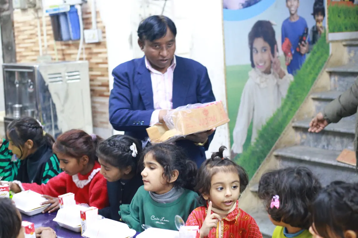 A pastor handing a wrapped gift to young children seated at a table
